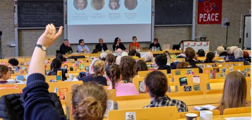 gefüllter Hörsaal mit Blick auf Panel der Konferenz Academia Under Attack